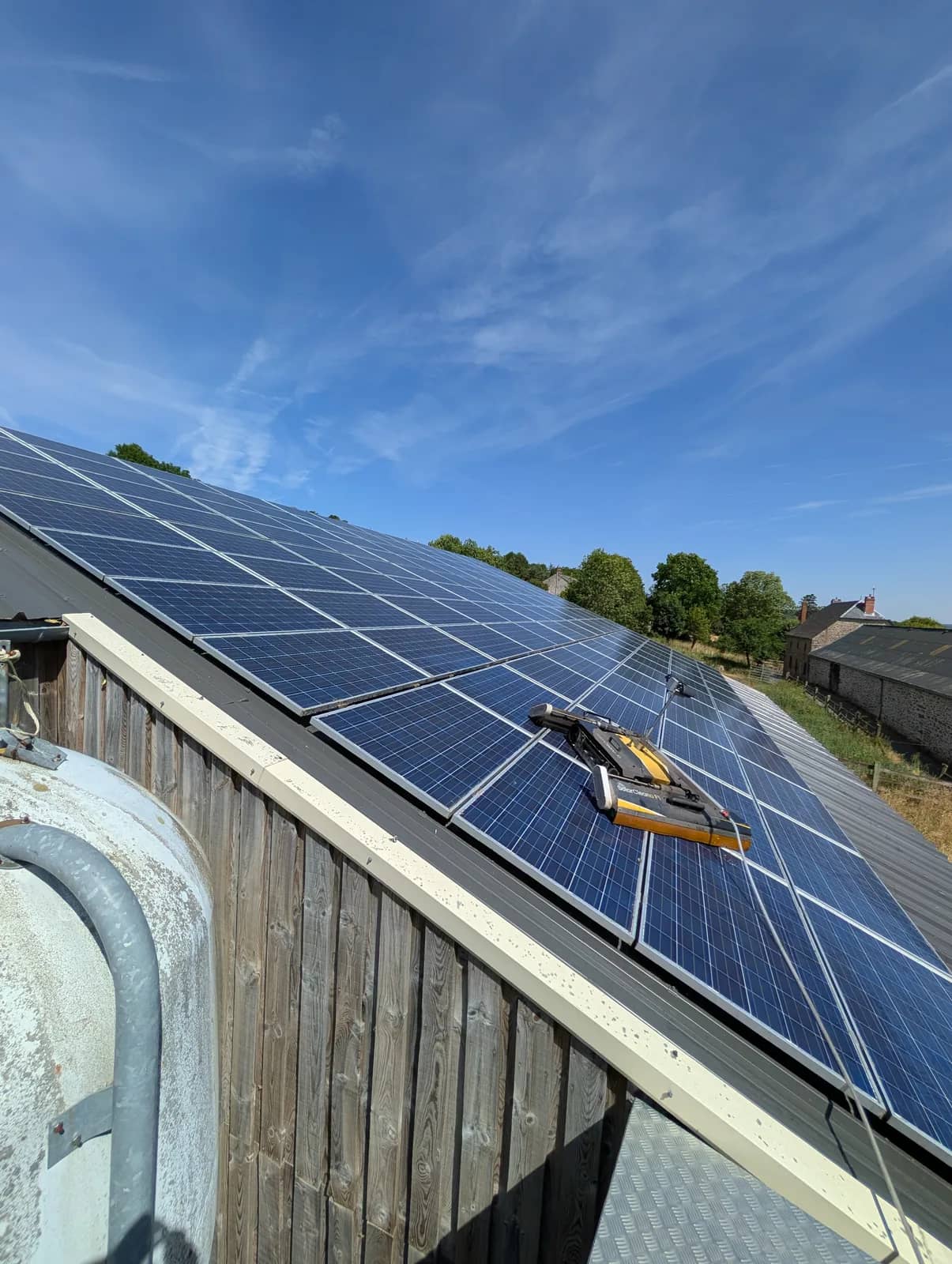 Robot SolarCleano sur une toiture de panneaux en pente, au-dessus d'un bardage en bois