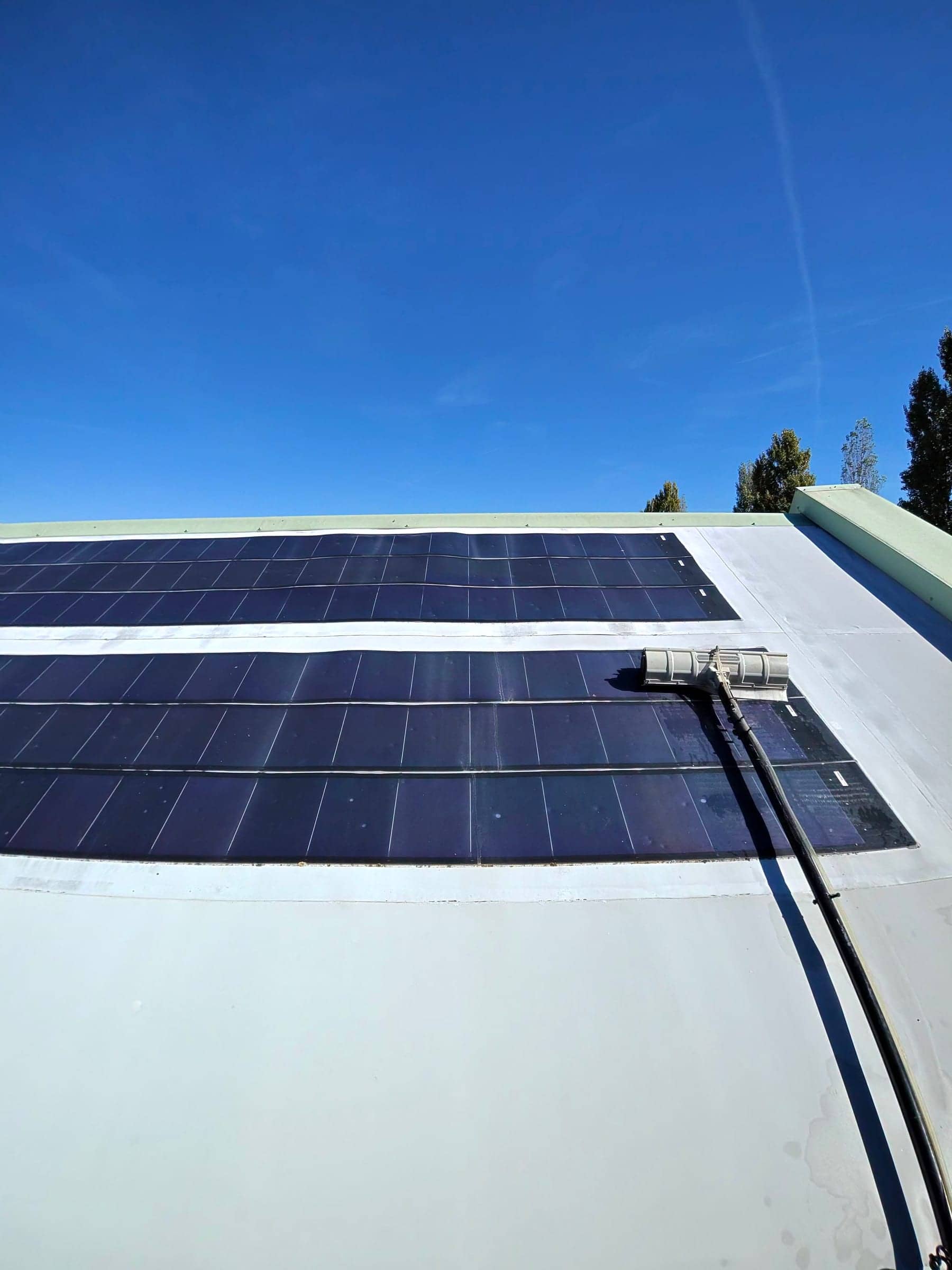 Rangées de panneaux photovoltaïques sur une toiture blanche sous un ciel bleu intense